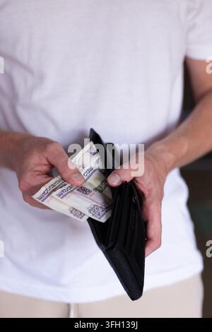 Homme prenant 100 pesos cubains dans un portefeuille. Banque D'Images