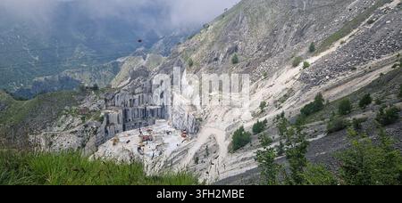 Vue pittoresque depuis la route d'un site d'extraction de marbre actif entouré de pics escarpés des Alpes apuanes et de bas nuages. Passo del Vestito, Italie Banque D'Images