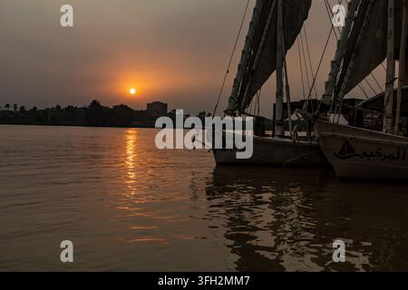 Vue des bateaux felouques traditionnels amarrés sur le Nil au coucher du soleil avec une lumière dorée se reflétant sur l'eau à Maadi en Sarayat Al Gharbeyah, Le Caire Banque D'Images