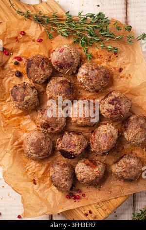 Boulettes de bœuf frits sur une planche en bois avec des herbes Banque D'Images