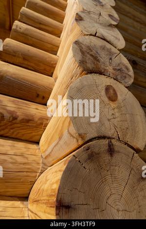 Une maison en rondins en bois avec des fissures aux extrémités, une maison en rondins centenaire faite de matériaux secs massifs forme le coin d'un bâtiment résidentiel Banque D'Images