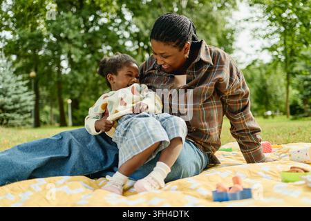 Mère noire heureuse jouant avec sa petite fille au parc Banque D'Images