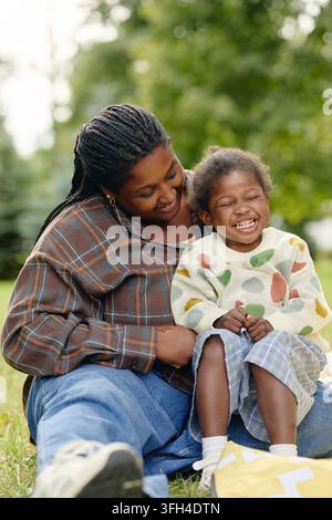 Mère noire heureuse se liant avec sa fille riante dans le parc Banque D'Images