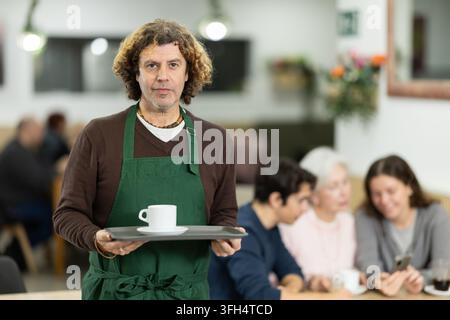 Barista masculin dans un café avec du café fraîchement préparé à partir de grains de qualité. Banque D'Images