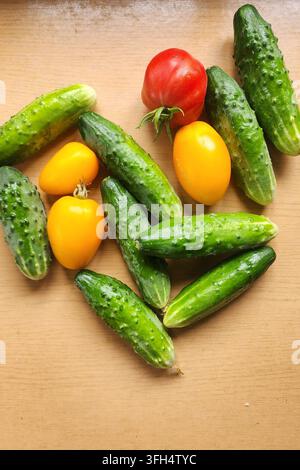 Cucurbitacées fraîchement cueillies et diverses tomates sur un fond en bois créant un cœur Banque D'Images