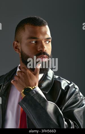Un jeune homme afro-américain beau pose avec une expression pensive, portant une tenue élégante. Banque D'Images