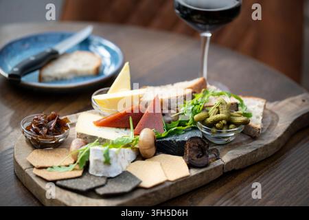 Un étalage coloré de fromages et de viandes disposés magnifiquement sur une planche en bois, parfait pour partager. Banque D'Images