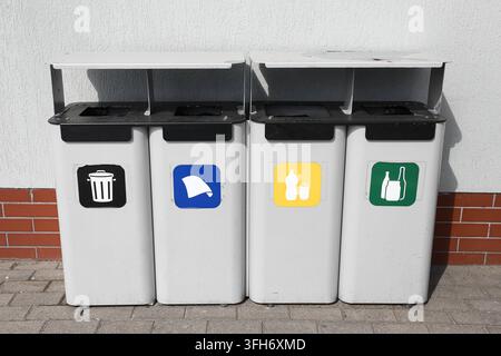 Bacs de tri des déchets avec des symboles de recyclage colorés disposés à l'extérieur. Fond de recyclage pour la séparation des ordures, la durabilité et la gestion des déchets. Banque D'Images
