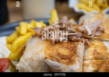 Assiette de shawarma délicieuse avec de la viande de poulet grillée sur une galette, des frites dorées et croustillantes et des légumes frais Banque D'Images