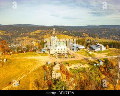 Vue aérienne de la tour d'observation Tanvaldsky Spicak et du refuge de montagne entourés de forêts d'automne et d'infrastructures de téléphérique dans les monts Izera Banque D'Images