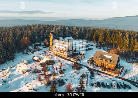 Vue aérienne de la tour d'observation Kralovka et de l'hôtel de montagne entourés d'une forêt de pins enneigée pendant l'heure dorée à Janov nad Nisou, Liber Banque D'Images