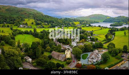 Vue aérienne du village de Grasmere entouré de campagne verdoyante dans le Lake District ; idéal pour les voyages au Royaume-Uni, le tourisme, l'immobilier et le marketing de destination Banque D'Images