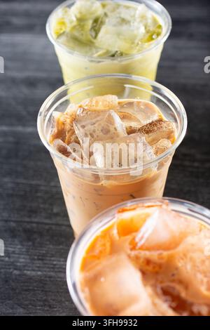 Une vue d'un set de trois boissons glacées dans des gobelets en plastique, thé thaïlandais vert, café vietnamien et thé thaïlandais. Banque D'Images