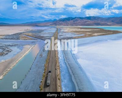 Vue aérienne des bassins d'évaporation de Morton Salt avec un camion sur une route de terre entre des étendues de sel colorées et une eau turquoise à Grantsville, Utah, États-Unis Banque D'Images