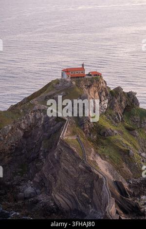 Vue de l'ermitage historique de Gaztelugatxe située sur un îlot rocheux avec un escalier en pierre sinueux menant depuis la mer Cantabrique en Espagne Banque D'Images