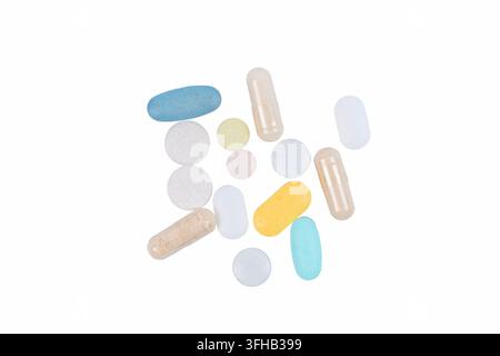 Pilules et capsules colorées assorties disposées sur un fond blanc Banque D'Images