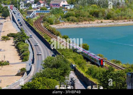 Train de Transport for Wales circulant le long de la voie ferrée à côté de la route côtière et de l'estuaire, vue en hauteur à Conwy, dans le nord du Pays de Galles Banque D'Images