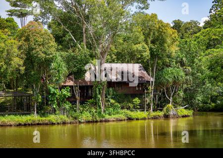 Hébergement éco en bois au bord de la rivière dans la forêt tropicale, Malaisie. Maison en bois isolée et bungalow nichés parmi des arbres verdoyants sur la rive du calme Banque D'Images