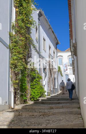 Tavira, Portugal, 12 avril 2024 : Vue sur l'une des ruelles pavées et étroites avec escaliers à Tavira, Algarve au Portugal Banque D'Images