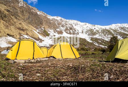 Camping de trekking avec tentes jaunes dans une vallée enneigée de l'Himalaya Banque D'Images