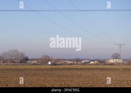 Szklarska Poręba, Pologne – 15 décembre 2025 : Le terrain agricole s’étend jusqu’à une zone de dépôt éloignée comportant des lignes de service, illustrant l’intersection Banque D'Images