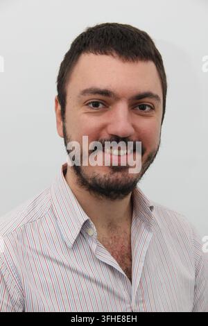 Homme barbu souriant en chemise rayée sur un fond neutre Banque D'Images