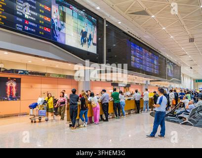 Taipei, Taïwan, 14 avr. 2024 – Une grande foule de voyageurs se rassemble autour des comptoirs d'enregistrement, certains avec des chariots à bagages, tandis que les départs numériques Banque D'Images