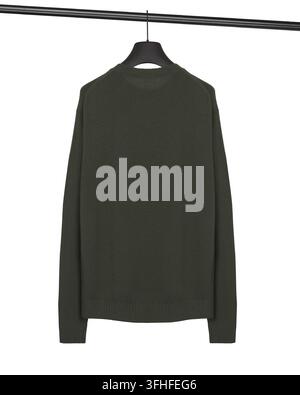 Un pull-over tricoté vert foncé uni à col rond suspendu à un cintre noir sur un fond blanc. Le vêtement a des manches longues, des poignets côtelés et a Banque D'Images