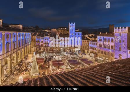 Vue du marché de Noël dans la Piazza Grande avec des projections lumineuses festives sur les bâtiments historiques et un grand sapin de Noël à Arezzo, en Toscane, Italie Banque D'Images