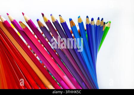 Crayons de couleur taillés disposés en éventail sur un fond blanc avec beaucoup d'espace libre, représentant la créativité, le dessin, l'éducation et l'art. Banque D'Images