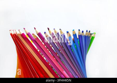 Crayons de couleur taillés disposés en éventail sur un fond blanc avec beaucoup d'espace libre, représentant la créativité, le dessin, l'éducation et l'art. Banque D'Images
