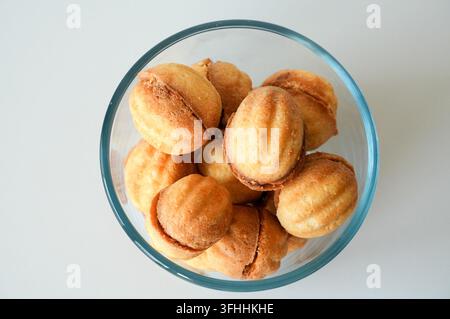 Petits biscuits dorés faits maison dans un bol sur fond blanc Banque D'Images
