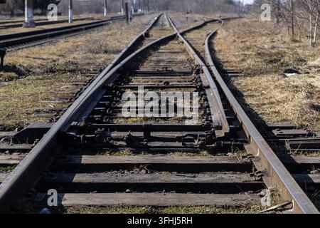 Les rails métalliques convergent à un point de jonction, montrant des appareils de voie dans un environnement rural tout en mettant en avant des thèmes de transport, log Banque D'Images