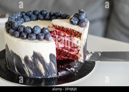 Gâteau red velvet en couches décoré d'un glaçage sombre et de myrtilles sucrées est servi sur une assiette moderne, mettant en valeur l'artisanat de la pâtisserie Banque D'Images