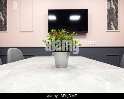 Une plante décorative artificielle centre un bureau en pierre grise dans une salle de réunion élégante, symbolisant un environnement de travail d'entreprise organisé et professi Banque D'Images