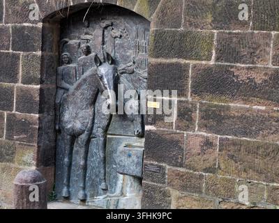 Une sculpture en relief en bronze détaillée représentant des chevaux et des figures humaines, insérée dans une niche en arc dans un mur en grès historique à Marburg, en Allemagne. Banque D'Images