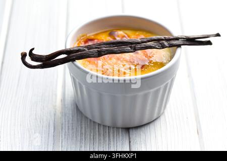Creme brulée dans un bol en céramique avec gousse de vanille Banque D'Images