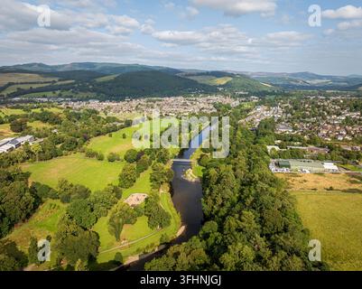 Vue aérienne de la ville de Peebles le long de la rivière Tweed, avec des champs verts, une forêt dense et des collines ondulantes sous un ciel lumineux à Peebles, Sco Banque D'Images