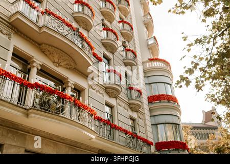 Belle façade de bâtiment avec balcons décorés de fleurs rouges.Maisons dans la grande ville européenne. Banque D'Images