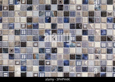 Motif de carrelage mosaïque géométrique bleu et beige. Gros plan de tuiles mosaïque bleues, grises, beiges, noires et blanches avec des motifs géométriques, rayés et texturés variés Banque D'Images
