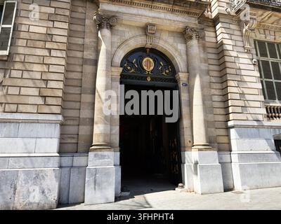 Entrée ornée baignée de soleil à Barcelone, Espagne, comportant un portail en arc, des colonnes, des ferronneries décoratives et une façade en pierre. Banque D'Images