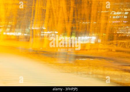 Traînées de lumière orange abstraites et mouvement urbain flou de nuit Banque D'Images
