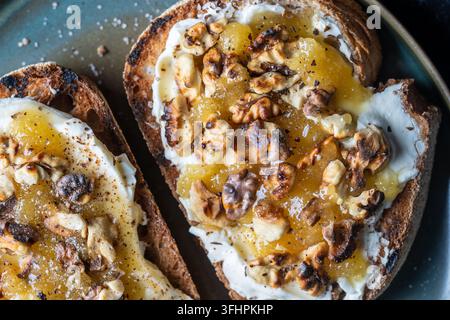 Deux toasts avec fromage à la crème, noix grillées, miel, poivre et sel sur l'assiette, vue rapprochée, vue du dessus Banque D'Images