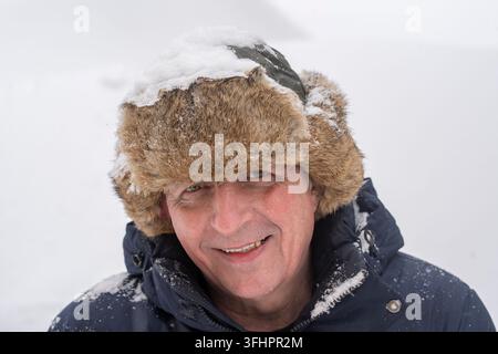 Homme ukrainien portant un chapeau d'hiver en fourrure sur fond de neige blanche, portrait en gros plan Banque D'Images