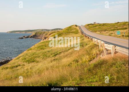 Une route côtière atlantique pittoresque le long de falaises herbeuses sous un ciel bleu ensoleillé, évoquant une atmosphère de campagne paisible, sentier Cabot, Cap-Breton, Nouvelle-Écosse Banque D'Images