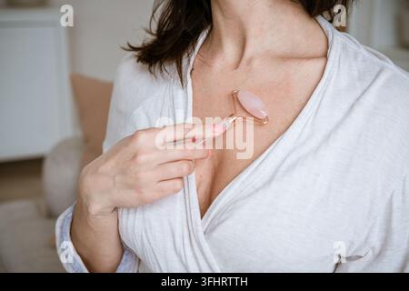 Portrait d'une femme beauté, soins de la peau, fille brune utilisant un rouleau sur une fraîcheur saine Banque D'Images