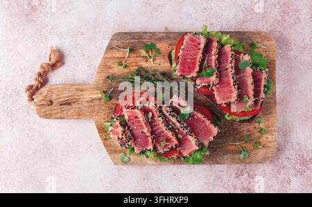 Sandwiches au filet de thon frit, dans des graines de sésame, sur une planche à découper en bois, pas de personnes, vue de dessus, fait maison Banque D'Images