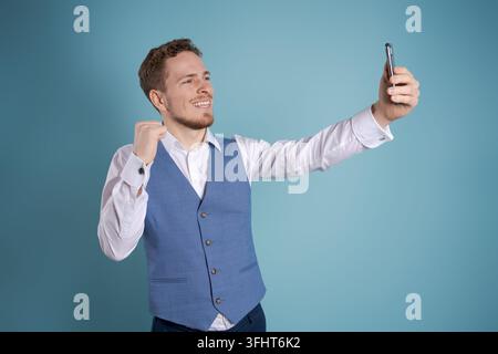 Jeune homme d'affaires souriant utilisant un smartphone pour contacter sa famille et ses amis ou Banque D'Images