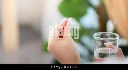 Prise de médicaments. Femme tenant la pilule et le verre d'eau pour la santé. Banque D'Images