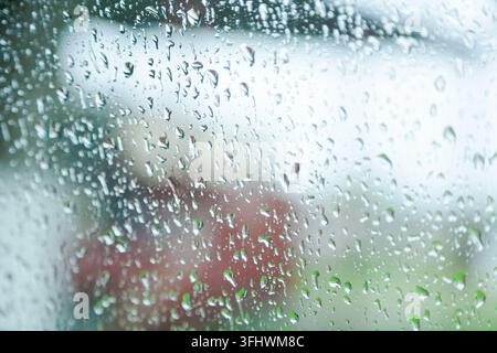 Gouttes de pluie sur une fenêtre. Les gouttes de pluie sont petites et dispersées. La fenêtre est claire et les gouttes de pluie sont visibles Banque D'Images